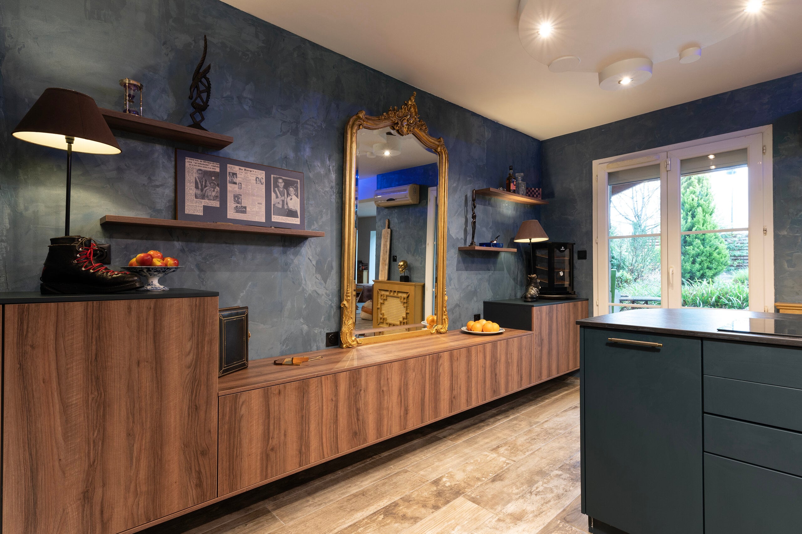 Cuisine aux murs bleus profonds avec armoires en bois et miroir doré