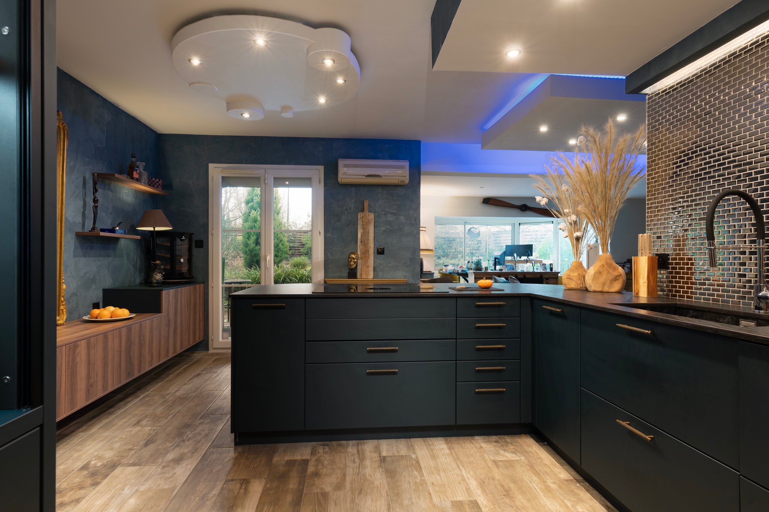 Cuisine avec placards sombres, sol en bois et crédence en mosaïque