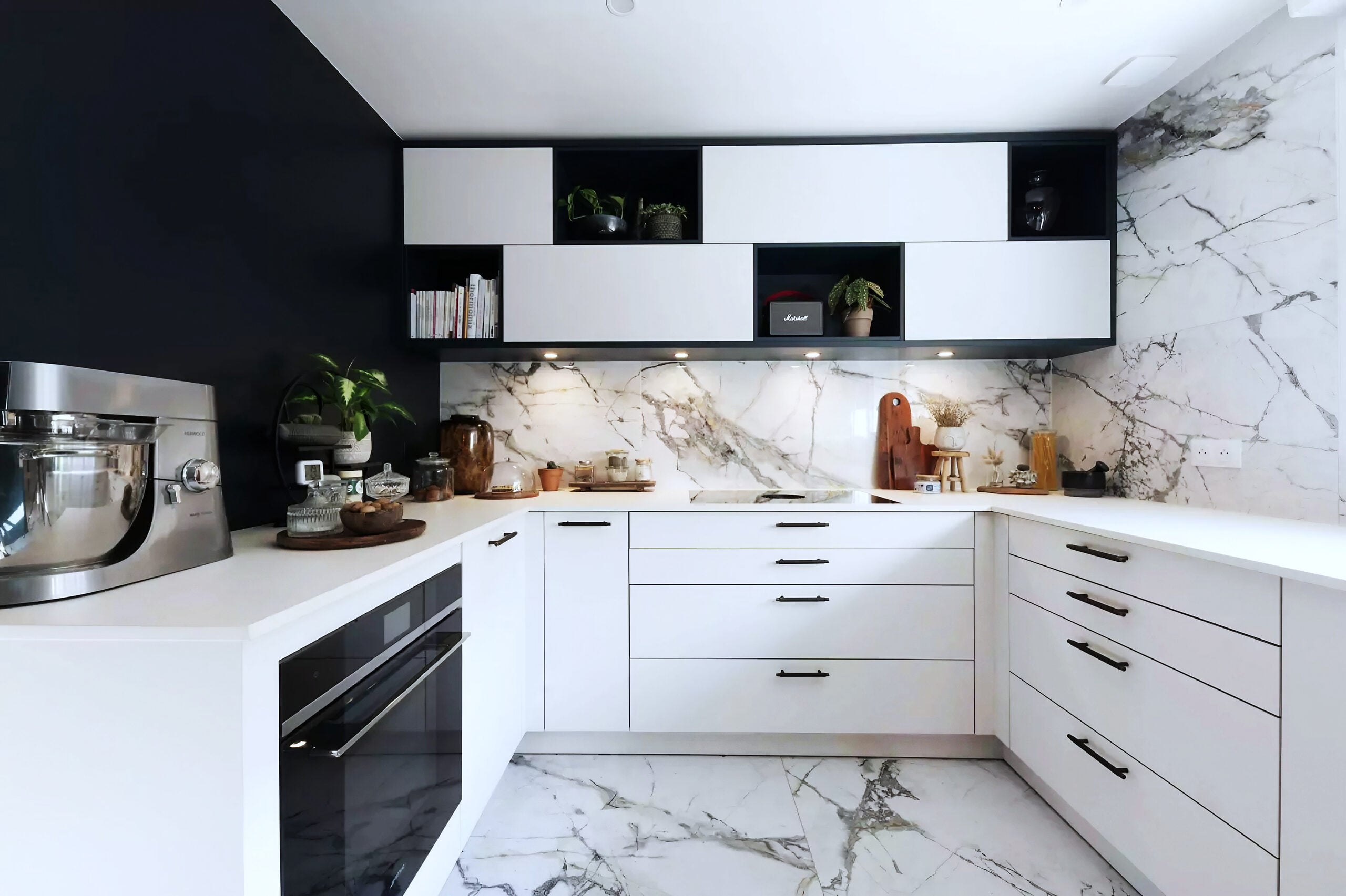 Cuisine aux armoires blanches, poignées noires et crédence en marbre