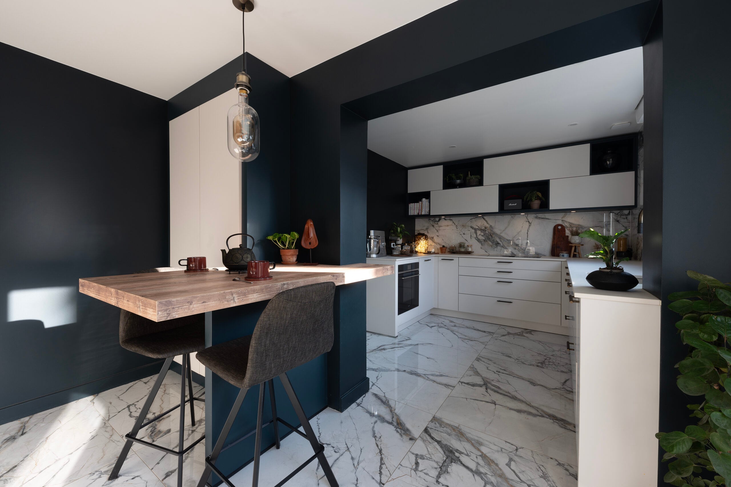 Cuisine avec murs bleu foncé, armoires blanches et sol en marbre