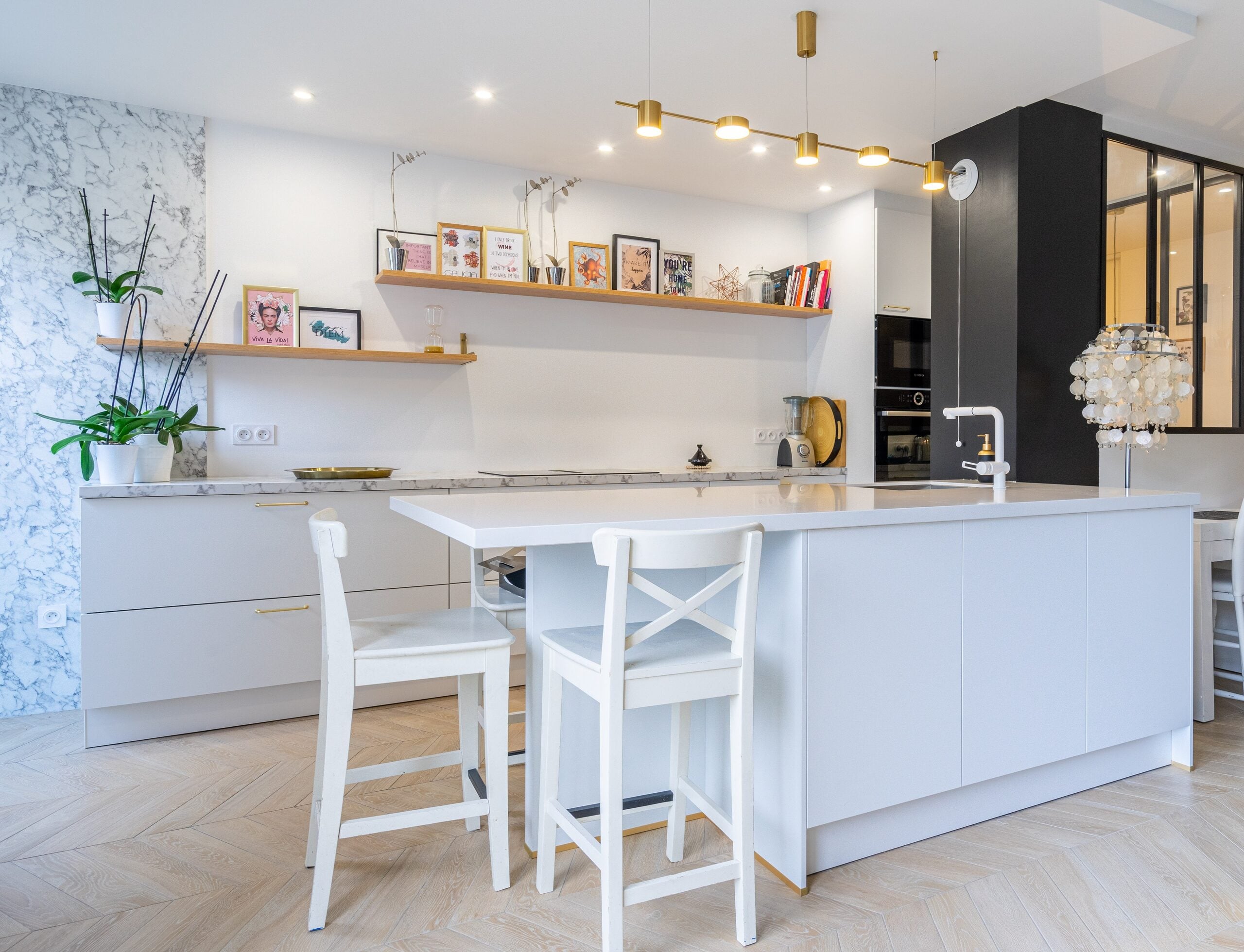 Cuisine entièrement blanche avec îlot central et sol en bois à chevrons