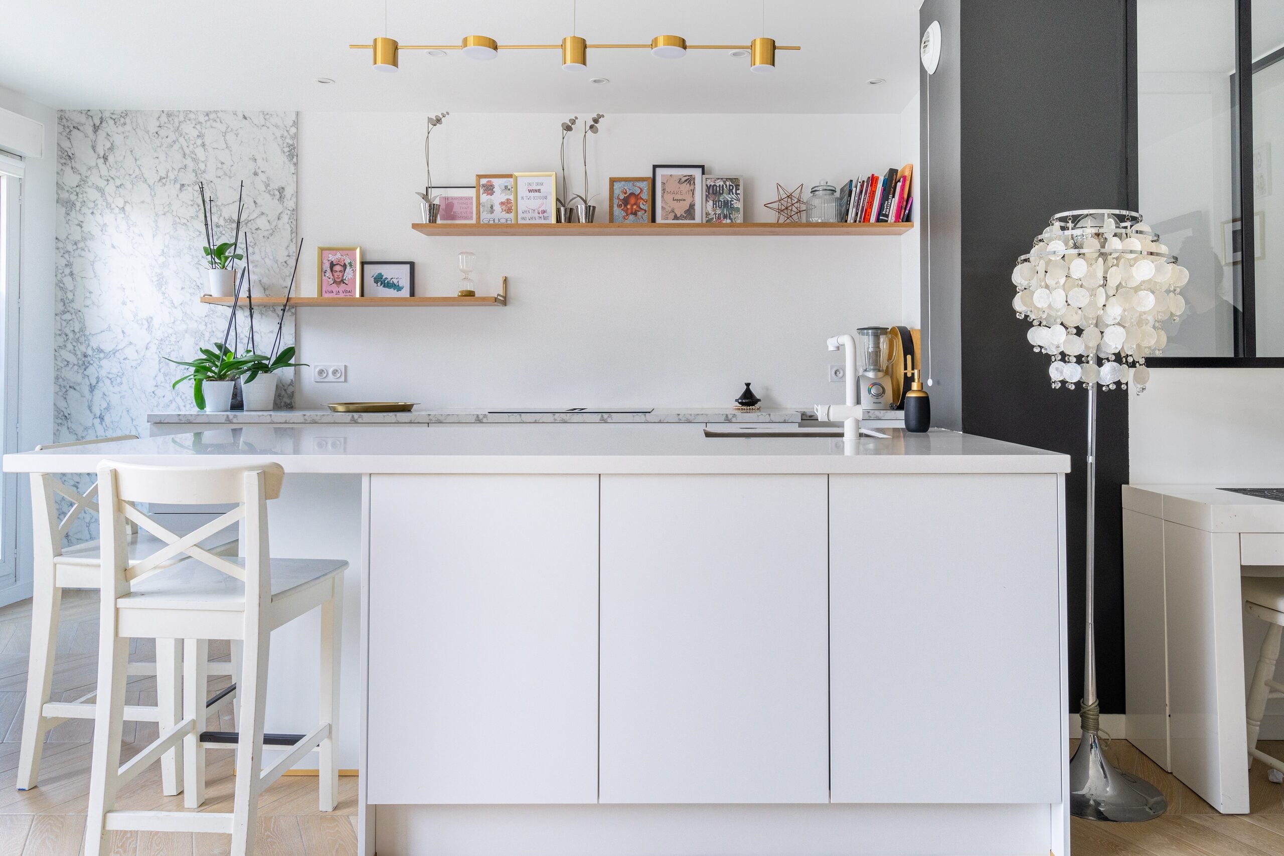 Cuisine épurée avec îlot blanc, sol en bois clair et touches de marbre