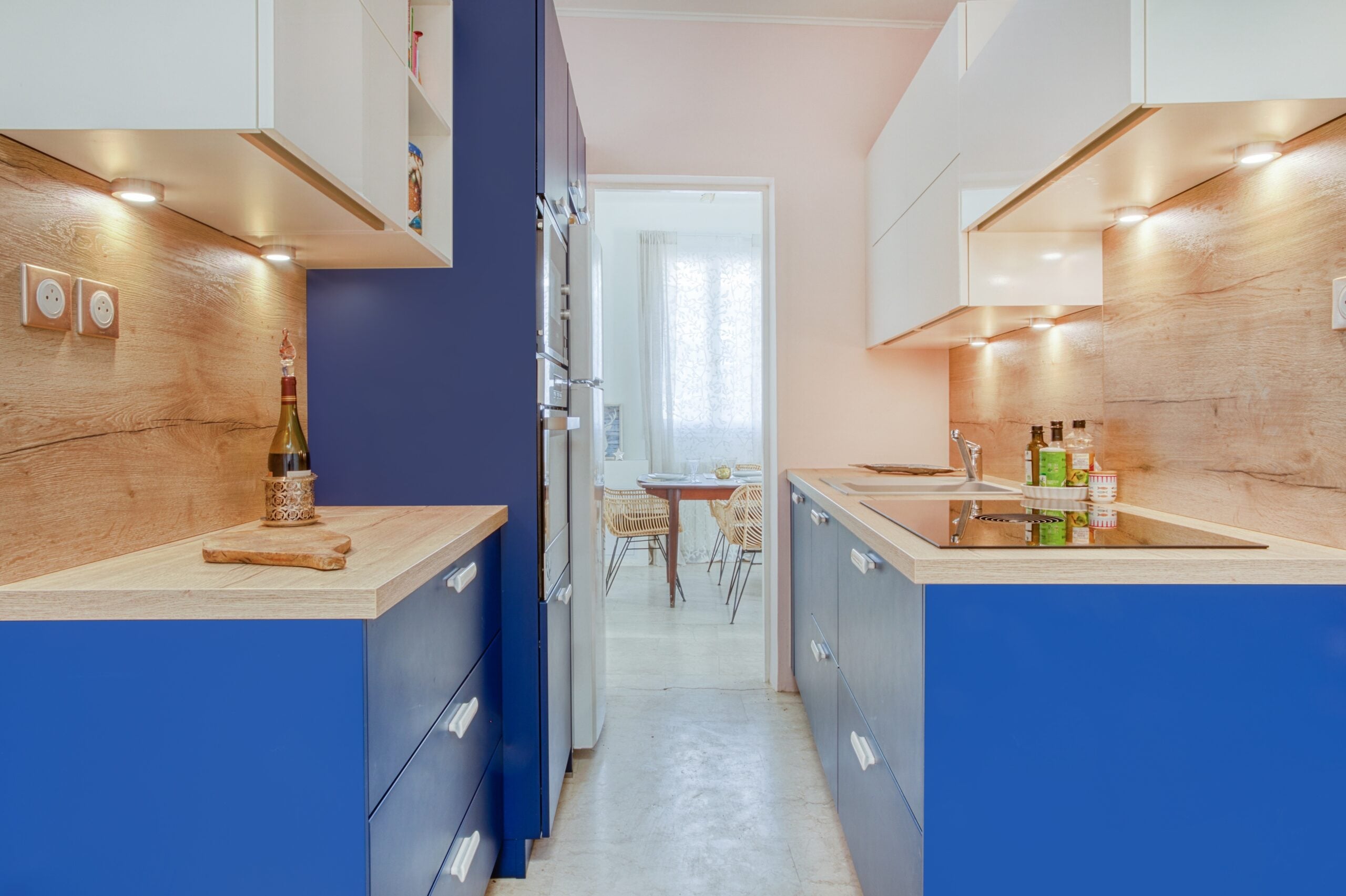 Cuisine avec armoires bleues en bas, comptoirs en bois et armoires blanches en hauteur