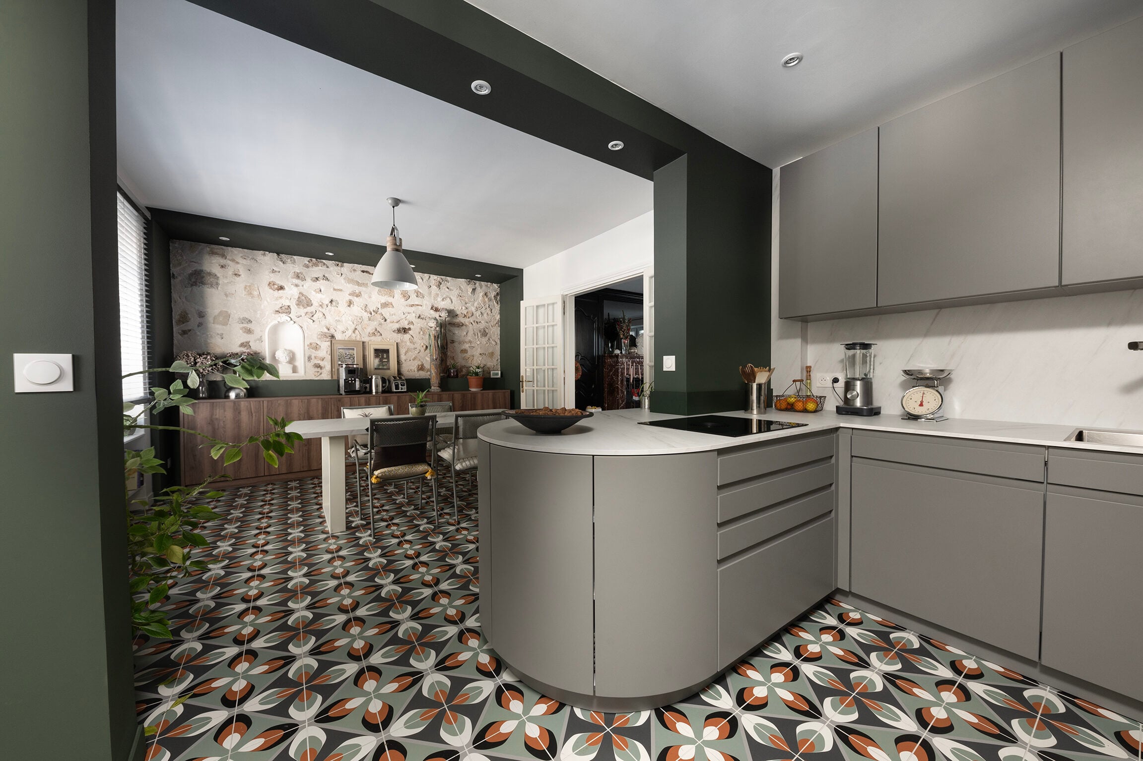 Cuisine avec armoires grises, comptoir en marbre et murs vert olive