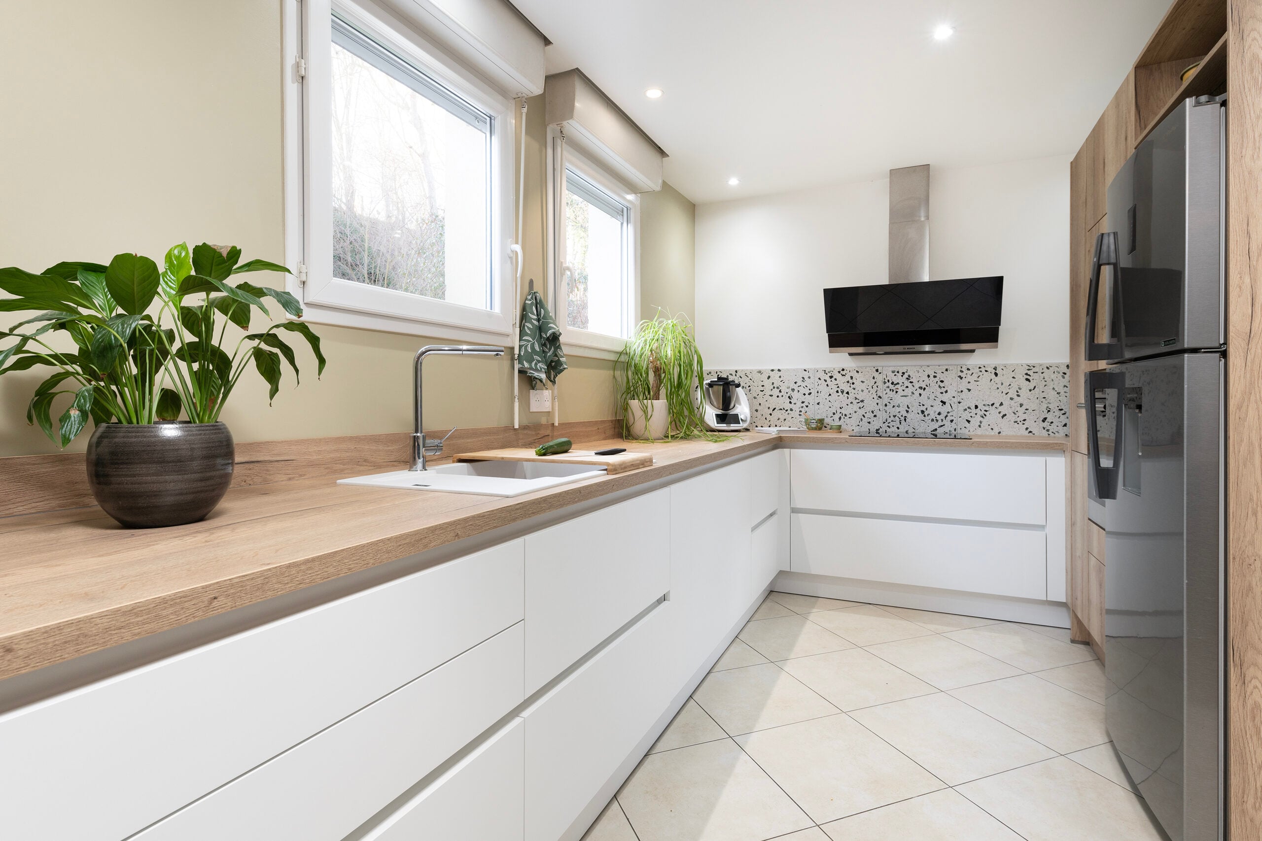 Cuisine longue blanche avec comptoirs en bois et hotte en inox