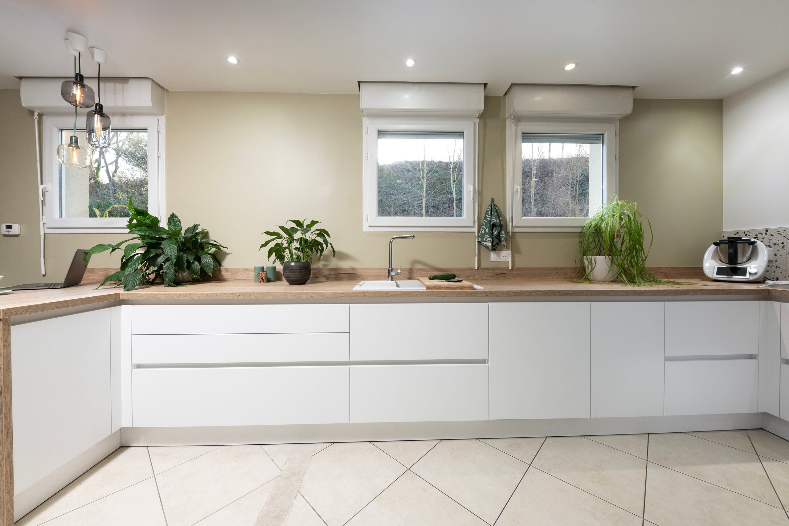 Cuisine blanche avec comptoirs en bois et murs beiges chaleureux