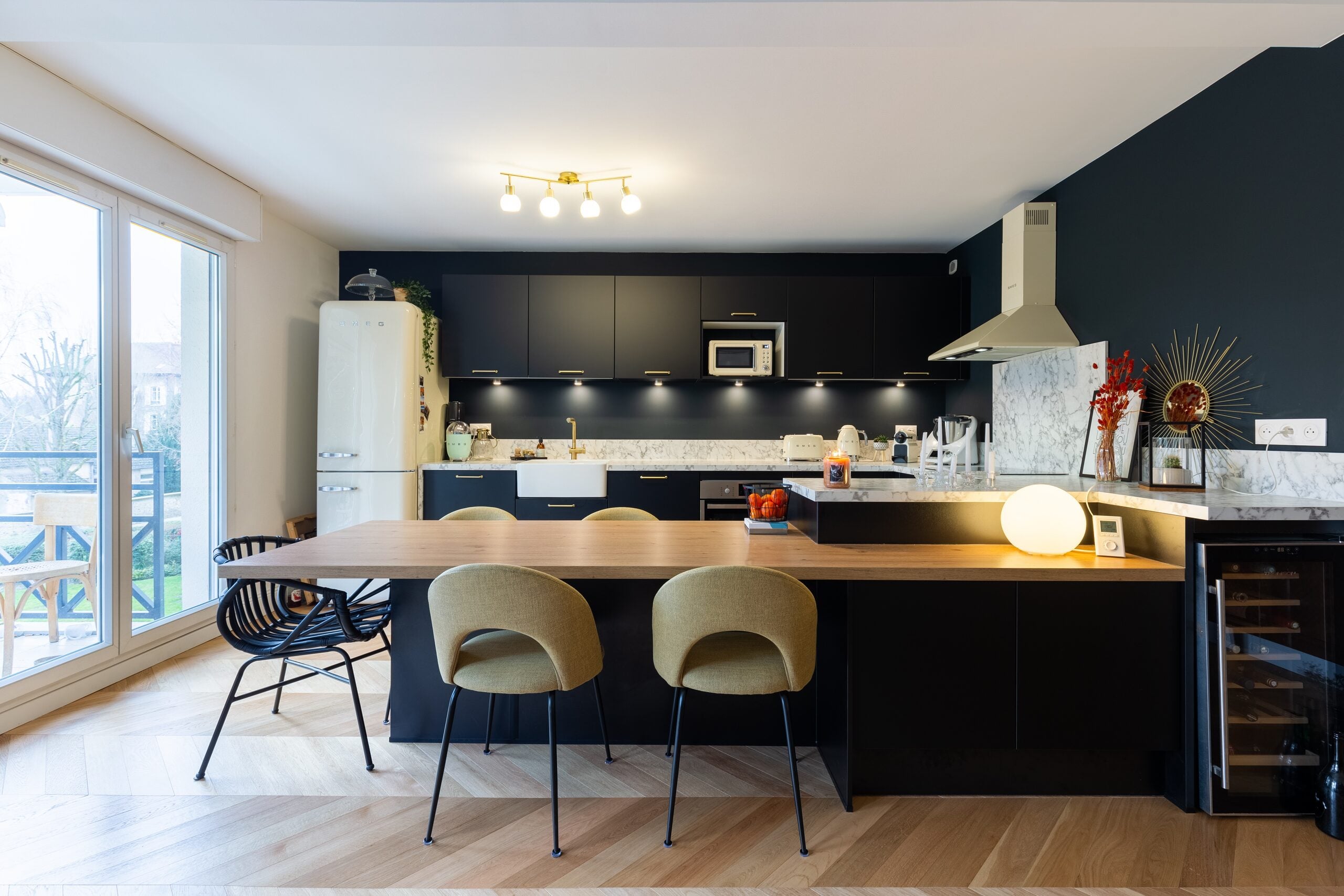 Cuisine marine avec armoires noires, îlot en bois et sol en bois clair