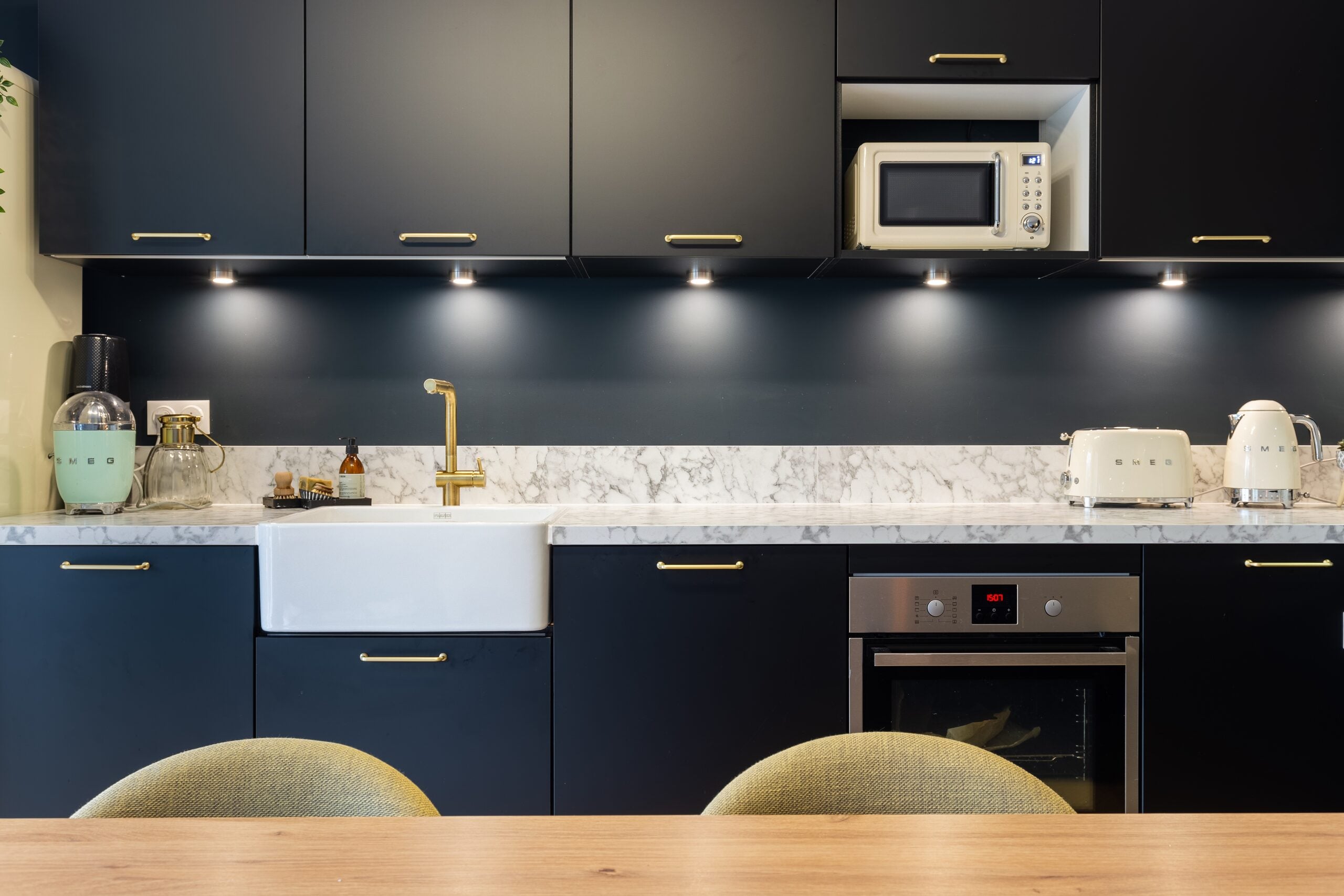 Cuisine sombre avec poignées dorées, plan de travail en marbre et évier intégré