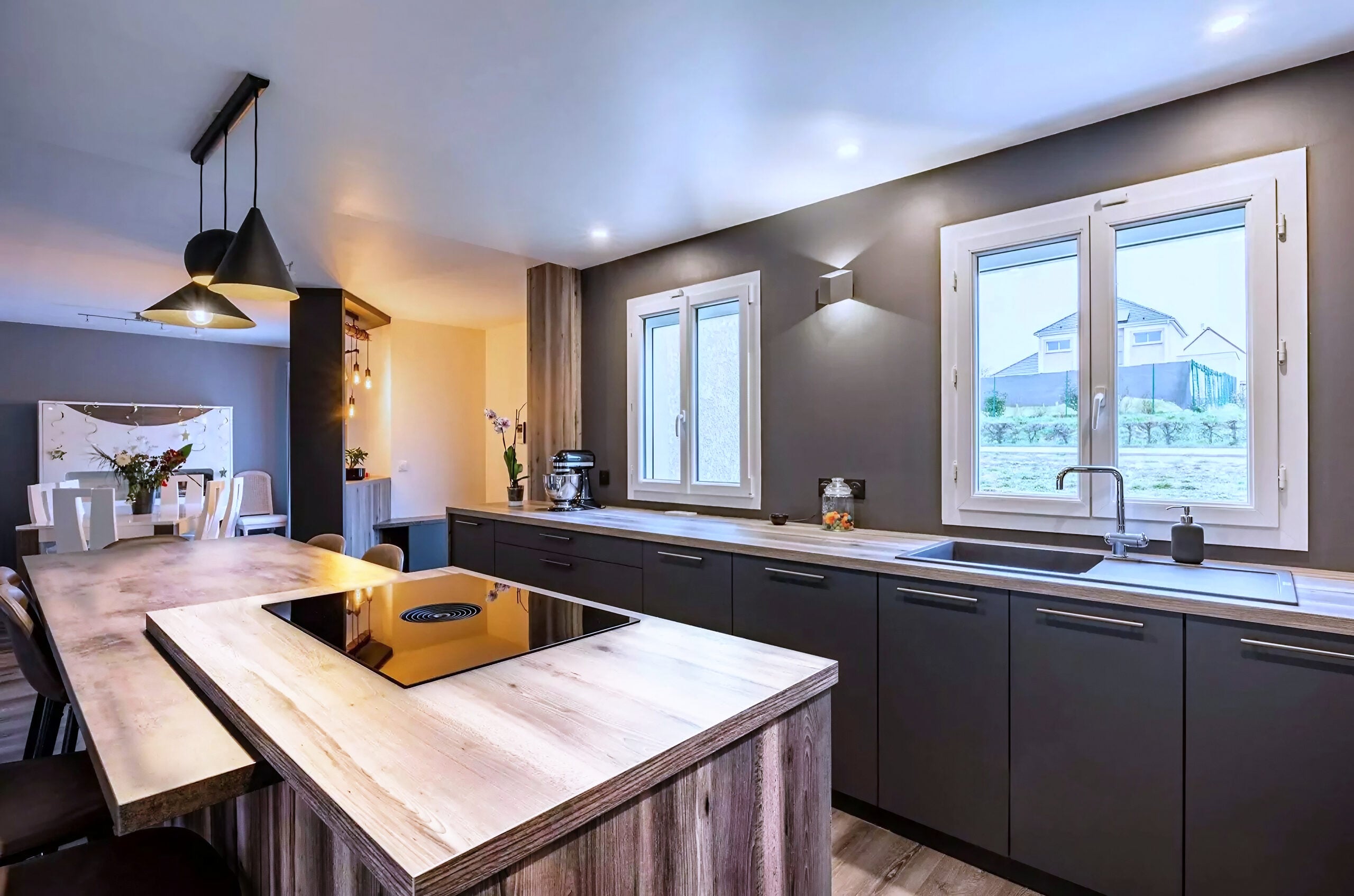 Cuisine avec îlot en bois, placards sombres et cuisinière encastrée