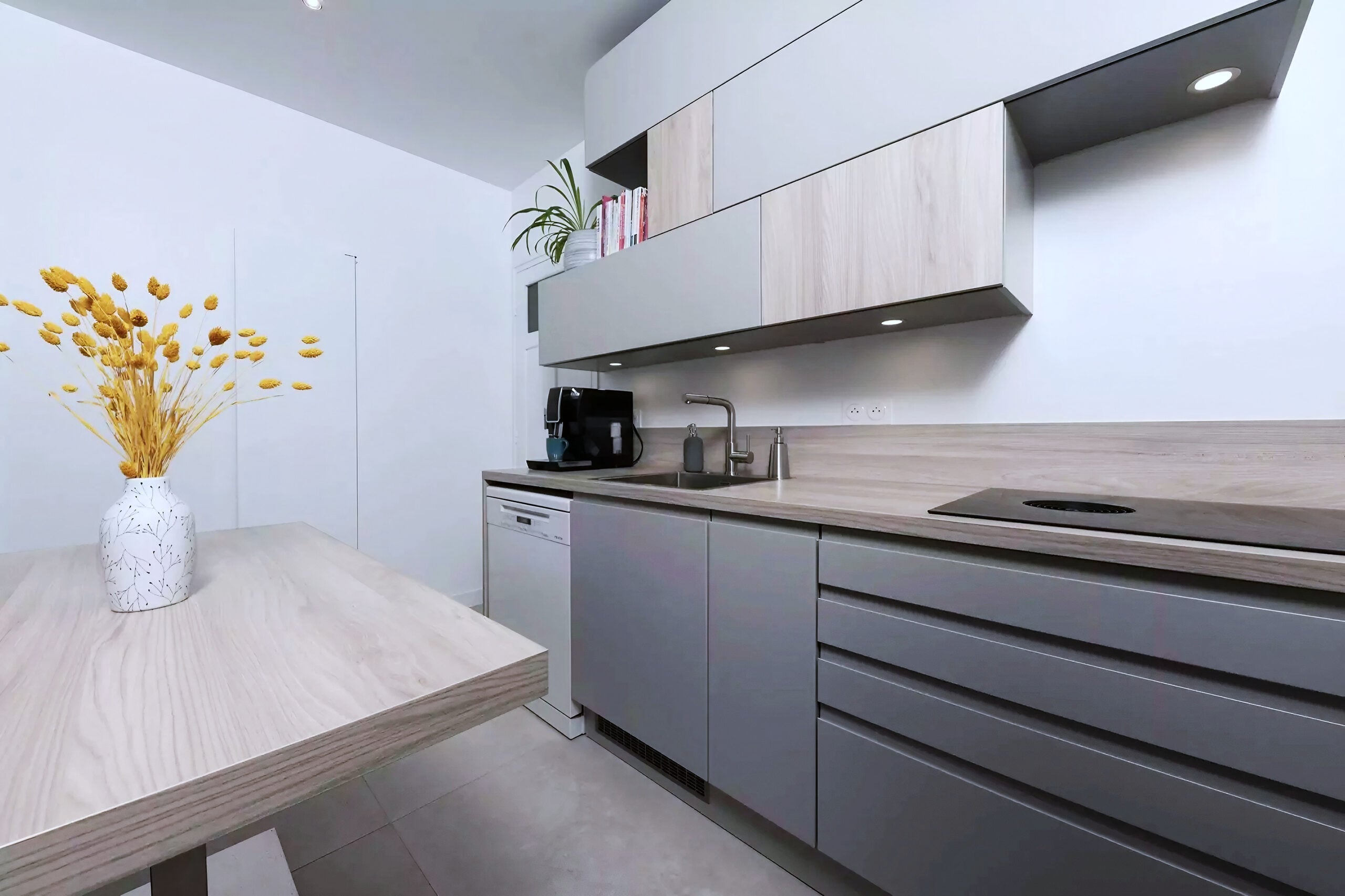 Cuisine studio avec armoires en bois clair et gris sur plan de travail foncé