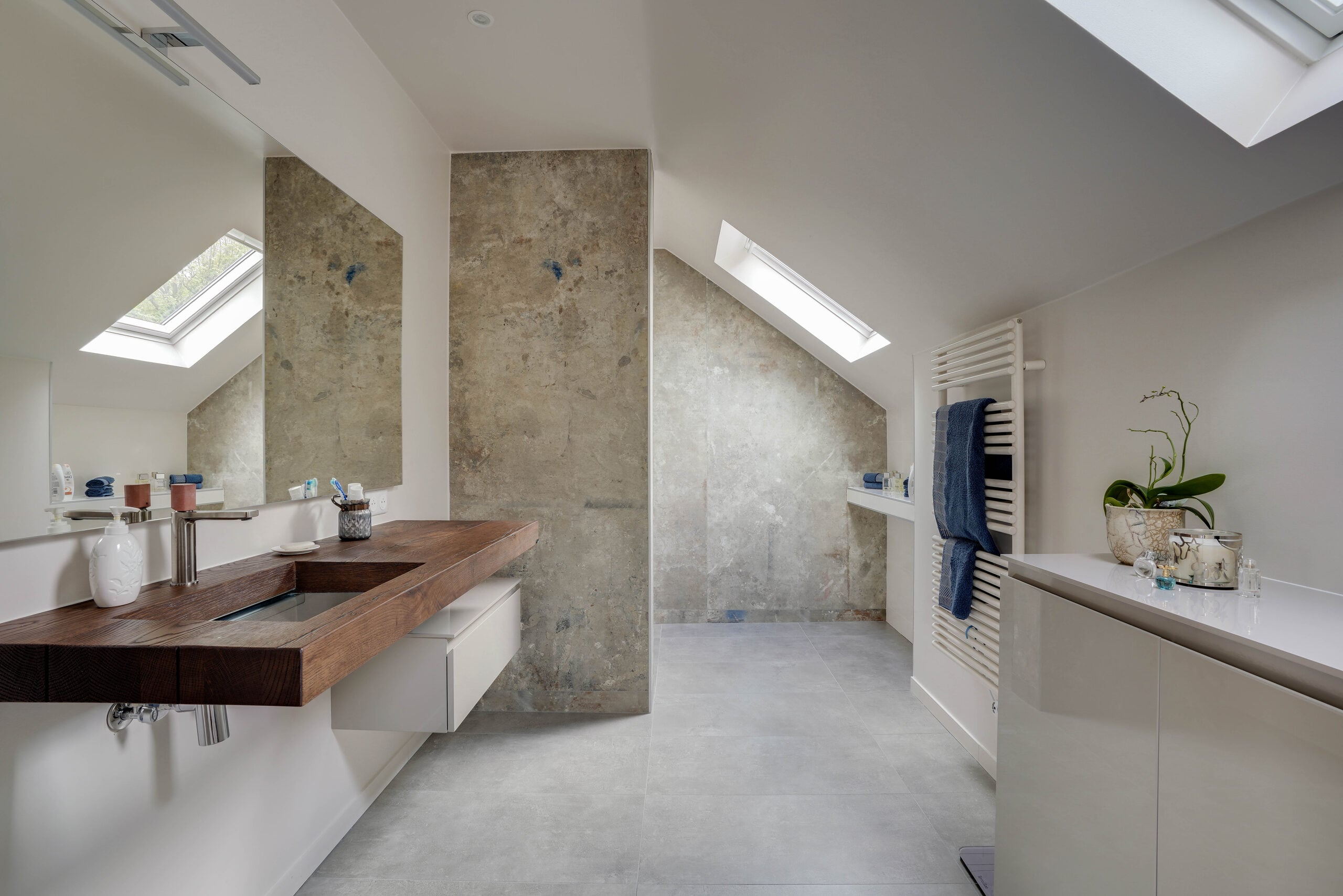 Salle de bains sous combles avec plan vasque en bois massif, velux, murs en pierre et douche italienne — réalisation Dec Home
